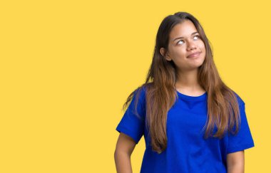 Görünümlü yan ve dik dik bakma uzağa düşünce gülümseyen izole arka plan üzerinde mavi t-shirt giyen genç güzel esmer kadın.