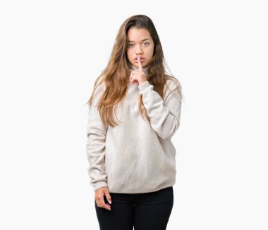 Dudaklarında parmak ile sessiz olmanı izole arka plan üzerinde boğazlı kazak giyen genç güzel esmer kadın. Sessizlik ve gizli kavramı.