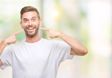 Tecrit edilmiş, güler yüzlü, kendine güvenen, parmaklarını, dişlerini ve ağzını gösteren genç yakışıklı bir adam. Sağlık kavramı.