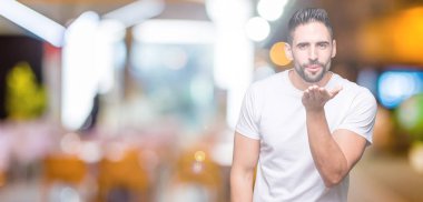 Bir öpücük el ile güzel ve seksi olmak hava üfleme kamera bakarak izole arka plan üzerinde rahat beyaz t-shirt giyen genç adam. Aşk ifade.