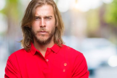 Yakışıklı delikanlı izole arka plan şüpheci ve sinir, onaylamayan ifade yüz çapraz kolları olan uzun saçlı. Negatif kişi.