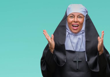 Orta yaş üst düzey Hıristiyan Katolik Rahibe kadın kutluyor izole arka plan üzerinde şaşırttı ve başarı için kaldırdı kollarını açarak hayret ve gözleri açık. Kazanan kavramı.