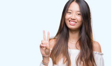 Genç Asyalı kadın gösterilen ve parmakları ile işaret izole arka plan üzerinde ikincisi ise kendinden emin ve mutlu gülümseyerek.