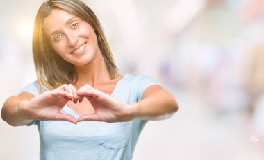 Genç güzel kadın kalp simgesi ve elleriyle şekil gösterilen aşık gülümseyen izole arka plan yüzünden. Romantik kavramı.