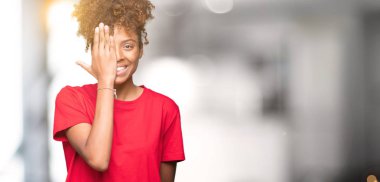 El yüz ve sürpriz duygu kendinden emin gülümseme ile tek gözüyle kapsayan izole arka plan güzel genç Afro-Amerikan kadın.