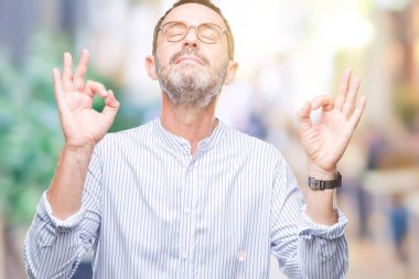 Orta yaş ağarmış komuta sizde gözlük izole arka plan üzerinde dinlenmek ve gülümseyen gözlerle kapalı parmak jestle meditasyon yapıyor. Yoga kavramı.