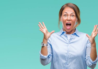 Orta yaş üst düzey İspanyol kadın deli kutluyor arka plan izole ve başarı için kaldırdı kollarını açarak hayrete ve heyecanlı çığlık gözleri açık. Kazanan kavramı