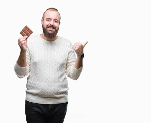 Jonge Hipster Man Eten Chocoladereep Geïsoleerde Achtergrond Aan Wijzen Tonen — Stockfoto