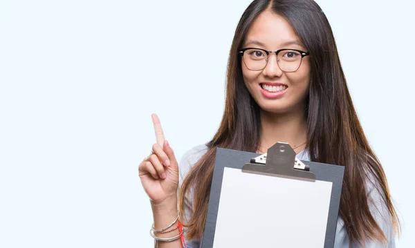 若いアジア ビジネス女性持株クリップボード上分離アイデアや質問 ナンバーワンの幸せそうな顔で指を指していると驚かれる背景 — ストック写真