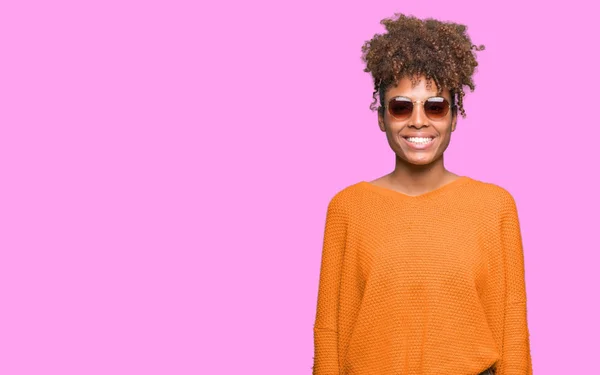 美丽的年轻非洲裔美国妇女戴着太阳镜在孤立的背景与一个快乐和冷静的笑容在脸上 幸运的人 — 图库照片