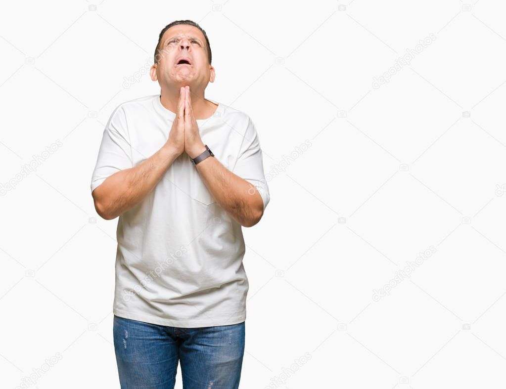 Middle age arab man wearig white t-shirt over isolated background begging and praying with hands together with hope expression on face very emotional and worried. Asking for forgiveness. Religion concept.