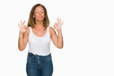 Güzel orta yaş izole arka plan rahat yetişkin kadın dinlenmek ve gülümseyen gözlerle parmak ile meditasyon jest yapıyor kapalı. Yoga kavramı.