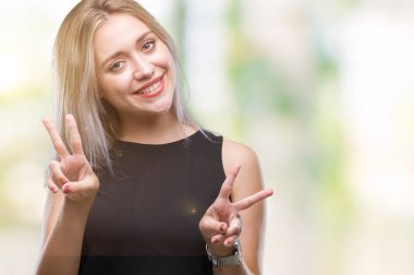 Genç Sarışın kadın parmaklarını zafer işareti yaparken gösterilen kamera seyir gülümseyen izole arka plan yüzünden. İki numaralı.