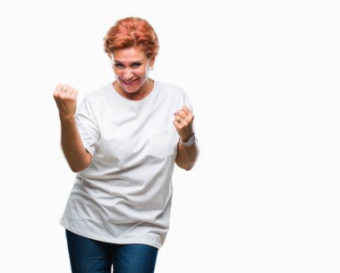 Gülümseyen ve başarı için çığlık Atrractive üst düzey beyaz Kızıl saçlı kadın izole arka plan çok mutlu ve heyecanlı kaldırdı, silah ile kazanan jest yapıyor. Kutlama kavramı.