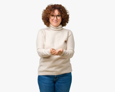 Gülen alma veya jest vererek birlikte el avuç içi ile arka plan güzel orta ager kadın kıdemli giyen boğazlı kazak ve izole üzerinde gözlük. Ayrı tutma ve koruma