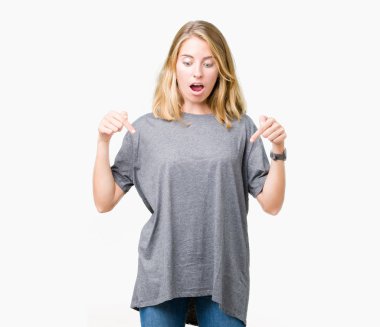 Güzel genç kadın giyiyor büyük boy rahat t-shirt üzerine izole arka plan aşağı işaret parmakları ile reklam, sürpriz yüz ve açık ağız gösterilen