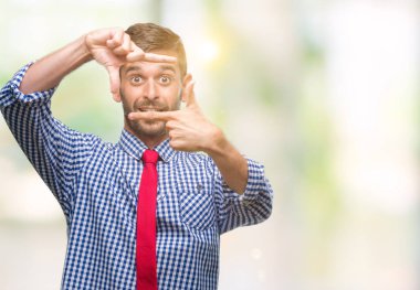 Genç yakışıklı iş adamı elle yapma çerçeve ve parmakları ile mutlu yüz gülümseyen izole arka plan üzerinde. Yaratıcılık ve Fotoğrafçılık kavramı.