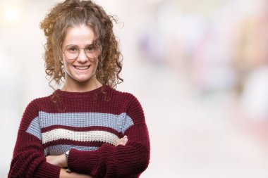 Güzel esmer kıvırcık saçlı Genç kız üzerinde gözlük takan mutlu yüz ile gülümseyerek kameraya seyir silah geçti arka plan izole. Olumlu bir kişi.