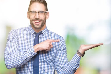 Hayret ve el ile sunulması ve parmak ile işaret ederken kameraya gülümseyen izole arka plan üzerinde gözlük takan genç iş adamı.