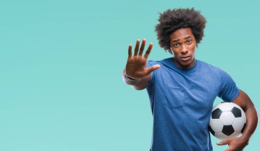Açık eliyle dur işareti ile ciddi ve kendine güvenen ifade, savunma jest yapıyor izole arka plan üzerinde futbol topu tutan Afro Amerikalı adam