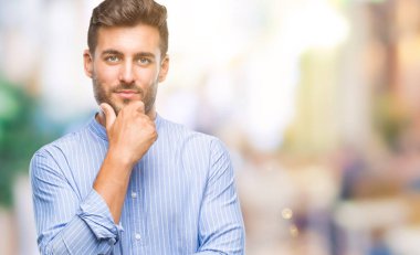 Yakışıklı delikanlı emin çapraz kollar ve çeneme kaldırdı el ile gülümseme ile kameraya bakarak izole arka plan üzerinde. Pozitif düşünce.