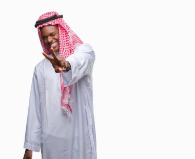 Geleneksel keffiyeh zafer işareti yapıyor parmak gösterilen kamera seyir gülümseyen izole arka plan üzerinde giyen genç Arapça Afrika adam. İki numaralı.