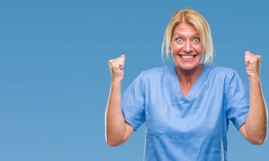 Orta yaş sarışın kadın doktor hemşire üniforması izole arka plan kutlama üzerinde şaşırttı ve başarı için kaldırdı kollarını açarak hayret ve gözleri açık. Kazanan kavramı.