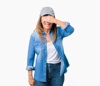 Güzel orta yaş kadın gülümsüyor ve gözleri için sürpriz kapsayan yüz el ile gülüyor izole arka plan üzerinde spor şapkası. Kör kavramı.