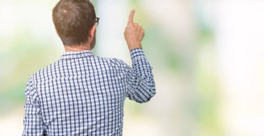 Yakışıklı orta yaş zarif komuta sizde gözlük izole üzerinden geriye doğru arkasında parmak eliyle işaret Posing arka plan