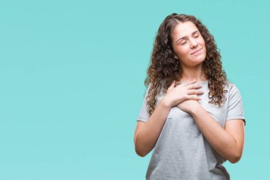 Casual göz kapalı gözler ile göğüs ellerinde ve yüzünde minnettar jest ile gülümseyen izole arka plan üzerinde giyen güzel genç esmer kıvırcık saçlı kız. Sağlık kavramı.