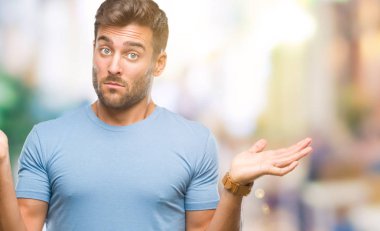 İzole arka plan clueless ve şaşkın bir ifadeyle kollar ve eller kaldırdı genç yakışıklı adam. Şüphe kavramı.