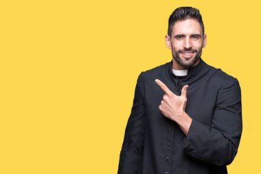 Genç Hıristiyan rahip izole arka neşeli bir gülümseme ile el ve parmak kadar yan yüzünde mutlu ve doğal ifade ile işaret yüz üzerinden