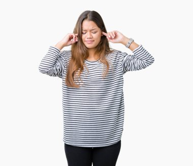 Yüksek sesle müzik gürültü rahatsız ifade parmaklarıyla kulaklarıyla kapsayan izole arka plan üzerinde çizgili süveter giyen genç güzel esmer kadın. Sağır kavramı.