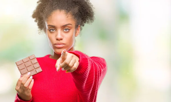 Junge Afroamerikanerin Isst Schokoriegel Vor Isoliertem Hintergrund Und Zeigt Mit — Stockfoto