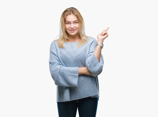 カメラを見ている側の手と指で指すの顔に大きな笑みを浮かべて隔離された背景に冬のセーターを着ている若い白人女性 — ストック写真