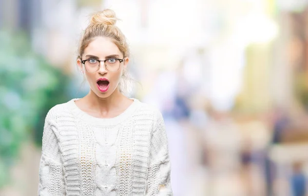 Young beautiful blonde woman wearing glasses over isolated background afraid and shocked with surprise expression, fear and excited face.