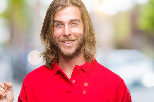 Young handsome man with long hair over isolated background with a big smile on face, pointing with hand and finger to the side looking at the camera.