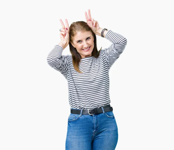 中年成熟的美丽的女人穿着条纹冬季毛衣在孤立的背景摆搞笑和疯狂的手指在头上作为兔子耳朵 微笑着欢快 — 图库照片