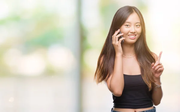 年轻的亚洲妇女在电话结束孤立的背景 惊讶于一个想法或问题手指与快乐的脸 — 图库照片