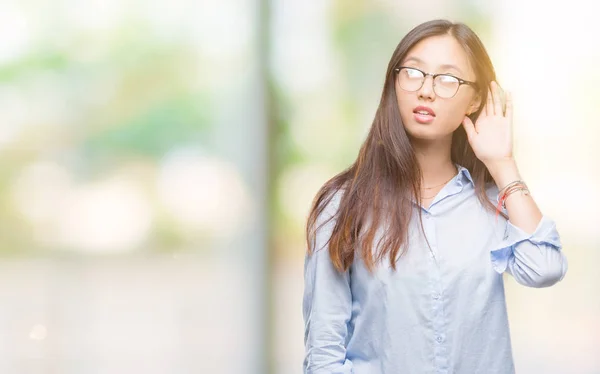 年轻的亚洲商业妇女戴眼镜在孤立的背景微笑与手在耳朵听谣言或八卦 耳聋概念 — 图库照片