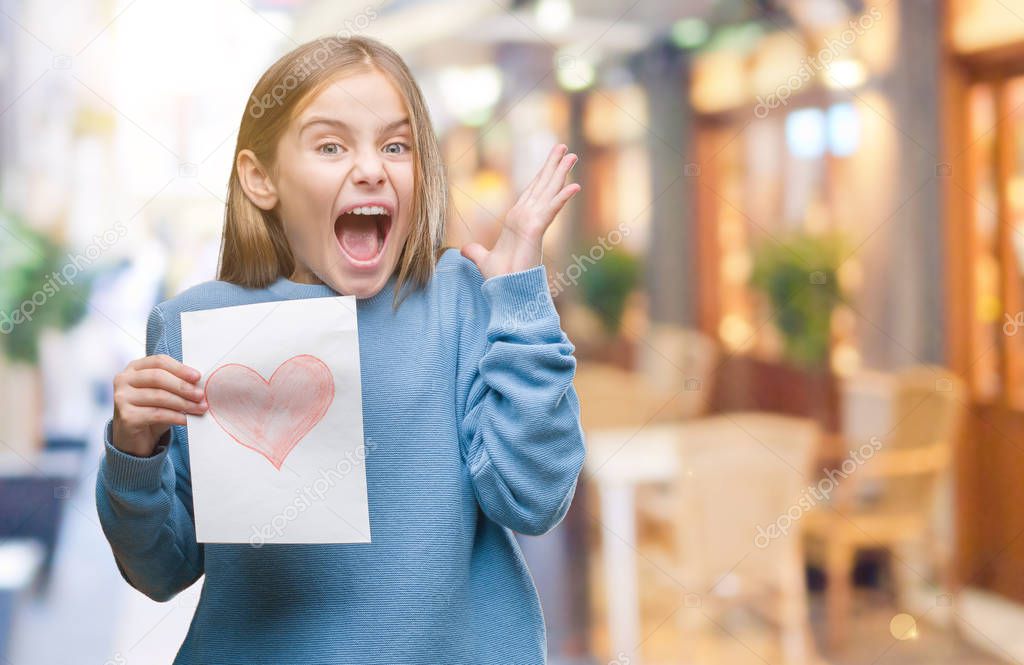 Young beautiful girl giving mother father day card with red heart over isolated background very happy and excited, winner expression celebrating victory screaming with big smile and raised hands