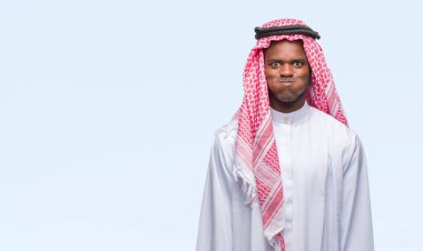 Komik surat ile yanakları şişirme izole arka plan üzerinde geleneksel keffiyeh giyen genç Arapça Afrika adam. Ağız ile hava, deli ifade şişirilmiş.