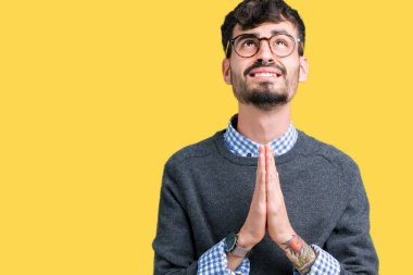 Yalvarıyor ve umut ifade yüzünde çok duygusal ve endişe ile birlikte elleriyle dua izole arka plan üzerinde gözlük takan genç yakışıklı akıllı adam. Bağışlanmak. Din kavramı.
