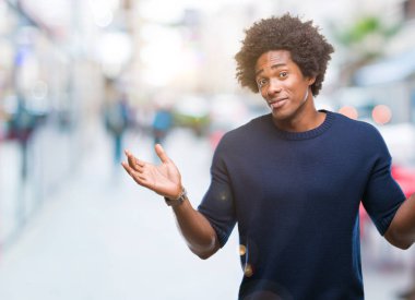 İzole arka plan clueless ve şaşkın bir ifadeyle kollar ve eller kaldırdı Afro Amerikan adam. Şüphe kavramı.