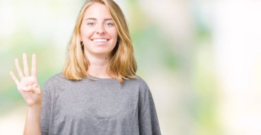 Gösterilen ve parmakları ile işaret izole arka plan üzerinde büyük boy rahat t-shirt giyen güzel genç kadın kendinden emin ve mutlu gülümseyerek süre dört numara.