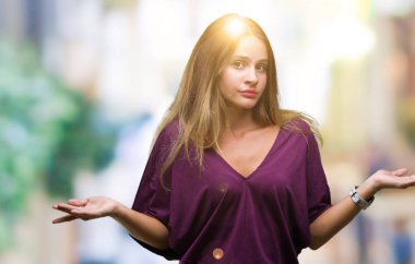 Genç güzel sarışın zarif kadın izole arka plan clueless ve şaşkın bir ifadeyle kollar ve eller kaldırdı. Şüphe kavramı.