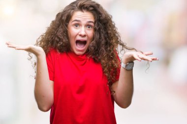 Rahat giyen güzel esmer kıvırcık saçlı Genç kız deli kutluyor izole arka plan üzerinde bakmak ve çığlık kaldırdı ve açık gözleri heyecanlı silah ile başarı için hayrete düşürdü. Kazanan kavramı