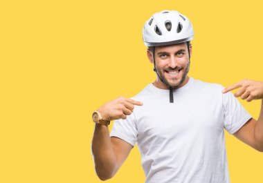Yüzünde gülümseme ile kendinden emin görünüyorsun, kendini gururlu ve mutlu parmakları ile işaret izole arka plan üzerinde bisikletçi Güvenlik kask giyen genç yakışıklı adam.