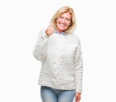 Orta yaş sarışın kadın hareketi el ile mutlu yaşasın yapıyor izole arka plan üzerinde kış kazak giyiyor. Kameraya bakarak başarı gösteren ile ifade onaylama.