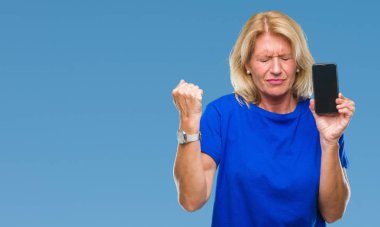 Orta yaş sarışın kadın gösteren boş ekran smartphone üzerinde izole arka rahatsız ve boşa çıkarmak ile öfke, çılgın ve yükseltilmiş eliyle diye bağıran öfke kavramı bağırarak.